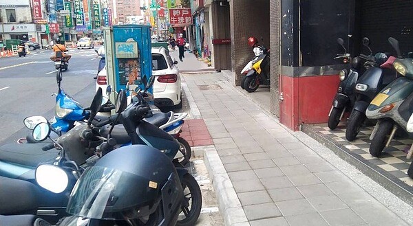 三重區正義北路人行道改善更新工程已部分完工,將人行道上的電箱、路燈、號誌桿等設施物整併。圖為其中一處改善後/新北工務局提供