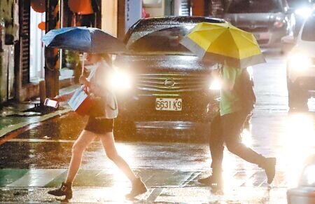 
軒嵐諾颱風2日持續接近台灣東北部，直至晚間為台灣北部帶來間歇性的風雨，民眾撐傘穿越馬路。（鄭任南攝）
