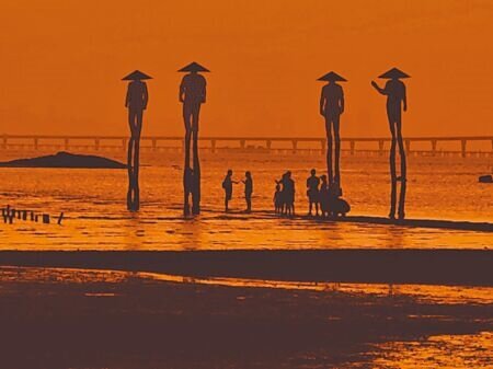 建功嶼夕陽餘暉中的「牡蠣人」與橫亙海上的金門大橋相映成趣。(李金生攝)