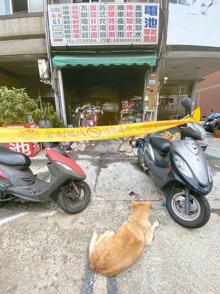等不到主人 高雄電池店屋主夫妻喪命，愛犬哈利獲救後，躺在燒毀的店面前不願離去。記者石秀華／攝影 