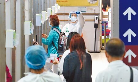 新冠肺炎本土疫情連4日破4萬例,昨日共新增4萬1430例本土、240例境外移入。圖為桃園機場採檢站,檢疫人員引導旅客排隊採檢。(范揚光攝)
