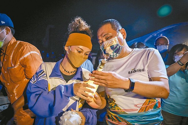 新北市金山高中學生引領市長侯友宜(右)放置代表思念與希望的「夜光信」。圖/新北市農業局提供