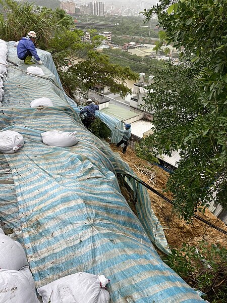 新北市汐止區伯爵街6巷底高壓電塔護坡坍方，台電已舖設帆布，防範災情不再擴大。圖／新北市工務局提供