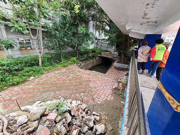 新北市議員鄭宇恩日前接獲家長反映,在八里國小校園內、司令台旁今年上半年突有塌陷成一大天坑,但經過近半年未有修復動作。圖/鄭宇恩服務處提供