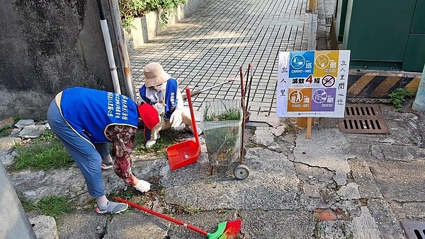 環保義工們仔細打掃里區每個角落，也隨手拔除路邊橫生的雜草。圖／吳碧麗提供
