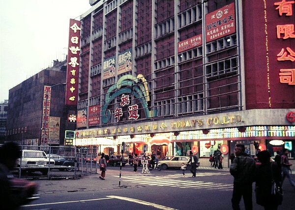 1972年12月,臺北市峨眉街和昆明街口,正在舉辦週年慶的今日百貨公司,可以看到隔壁的萬年商業大樓正在興建中。(張哲生提供)