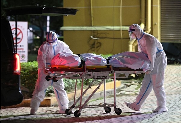 衛福部統計顯示,2021年死亡人數比前年多一萬一千人,引發「超額死亡」與「死亡黑數」的議論。圖為禮儀公司人員穿著全身防護衣將確診者遺體從醫院移出,準備運往殯儀館火化。記者劉學聖/攝影