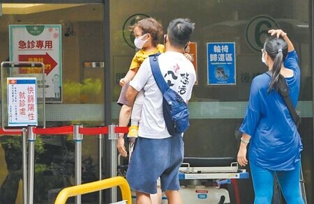 國內疫情有趨緩跡象,中央流行疫情指揮中心發言人莊人祥說,本土疫情要降到單日1萬例以下「恐怕沒那麼快」,目前看來可能要等到7月底。3日醫院的防疫急門診外,家長抱著小孩前來看診。(陳俊吉攝)