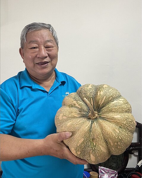 洪天化里長以及為了共餐而特別準備的有機南瓜。圖／蔡愷恆攝