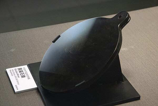 故宮北院展出存世數量極少的中美洲阿茲特克魔幻神鏡「阿茲特克帝國黑曜石鏡」,乾隆、道光皇帝都曾為此鏡題詩。黑曜石鏡雙面經精細打磨拋光,製作出高反射、高穿透的玻璃效果。圖/故宮提供