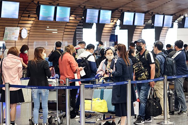 受新冠疫情影響,民眾已將近3年出遊受到很大限制,世界各國、台灣及日本都陸續宣布放寬入境政策,民眾想要出國旅行的心情也直接反應在班機訂位數。圖為桃園機場一航廈出境大廳,旅客在地勤櫃台前排隊辦理報到手續。記者黃仲明/攝影