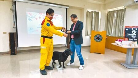 
搜救犬「巧克力」卸下工作裝備，換戴上可愛的項圈，由領犬員李信宏（左）交給認養人柯建昌（右）。（洪靖宜攝）

