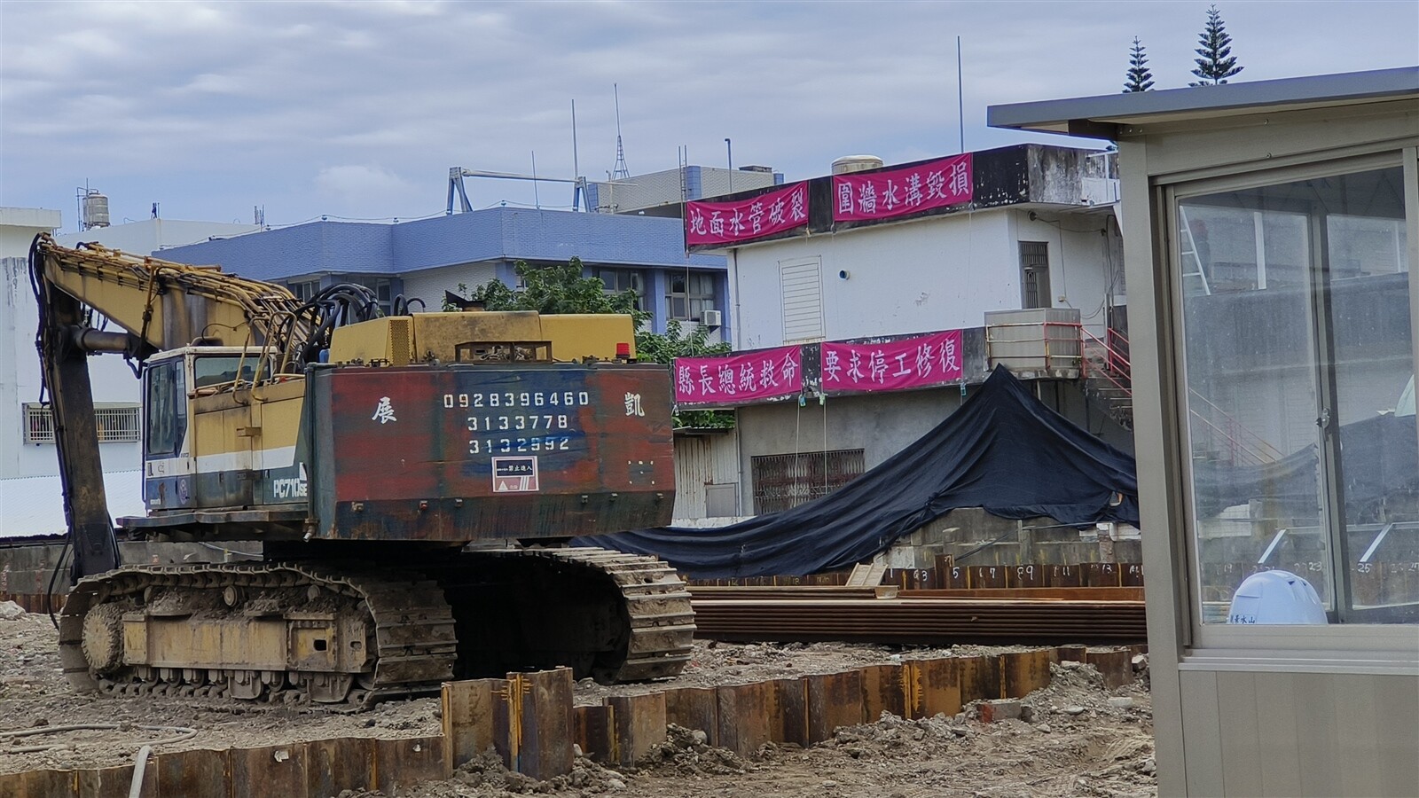 「海濱好室」社宅工地旁住戶，在外牆掛上紅布條向縣長總統求救。記者卜敏正／攝影 