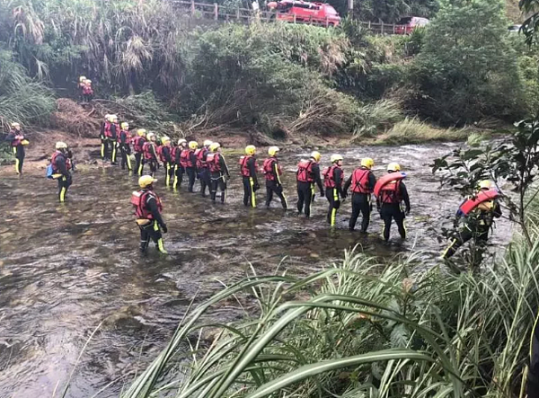 學員通過河床間砌石階梯「梳子壩」時,因水量瞬間暴漲,湍急水流將多人沖落北勢溪,六人溺水死亡,消防人員當時搜救情形。圖/新北市消防局提供