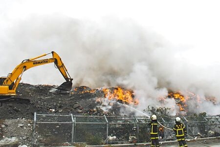 台東市垃圾掩埋場26日起火燃燒，消防人員與怪手全力滅火。（莊哲權攝）