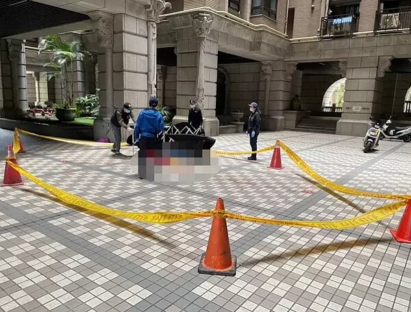 基隆市游姓女子昨天從麥金路居住的社區22樓頂樓墜地死亡，警方封鎖現場調查死因。圖／讀者提供
