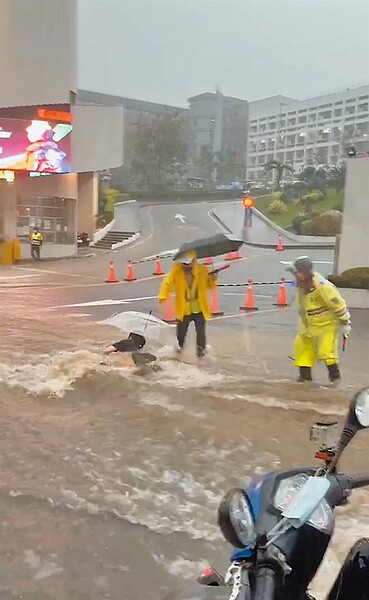 昨天上午的豪大雨造成台中各地淹水，一名疑似弘光科大女學生行經校門口不小心跌倒，被水流直接往前沖走數公尺。（取自記者爆料網）