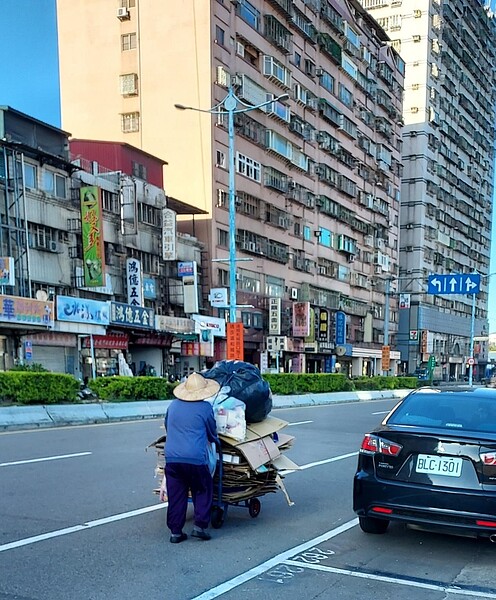 老婆婆吃力的推著資源回收車。圖／易小滿攝