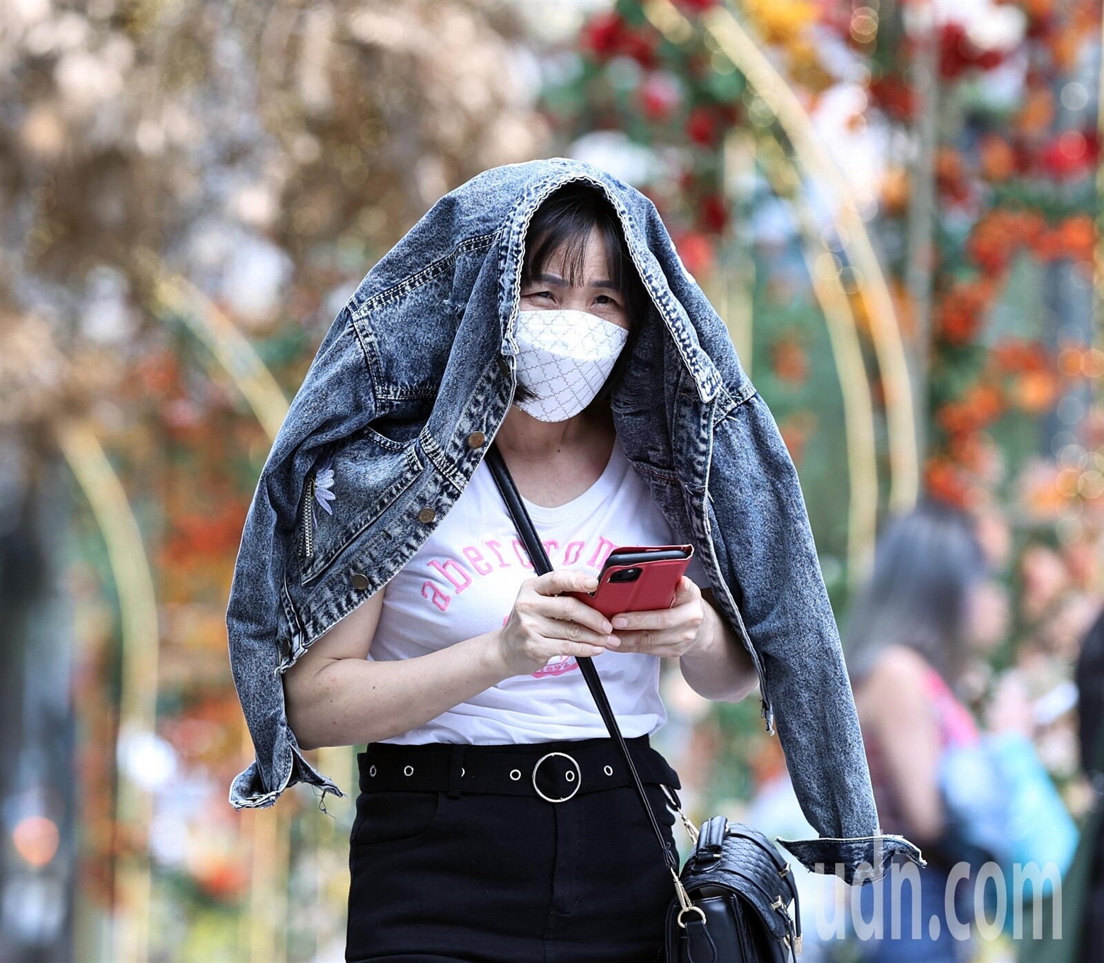 今天北部氣溫略顯炎熱，外出民眾將外套披在頭上遮擋豔陽。記者侯永全／攝影 