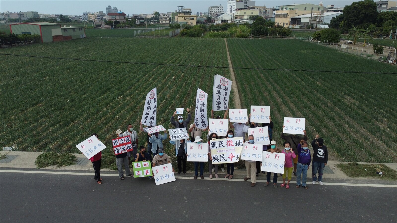 高雄捷運延伸林園線預定R6站體的沿線部分居民和地主,反對市府區段徵收土地,站在可能會被徵收的洋蔥田前,拿大字報表達抗議。記者劉學聖/攝影