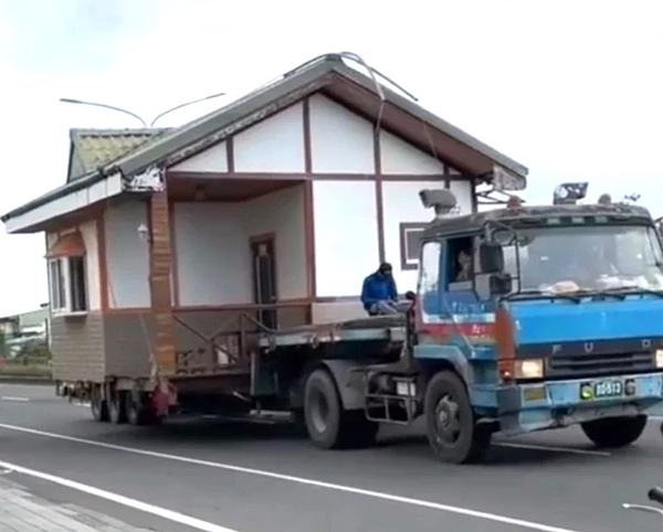1輛載運小木屋的拖板車行駛屏東縣恆春鎮台26線恆公路上,民眾拍下影片昨天PO上網路社群,有網友戲稱是「霍爾的移動城堡」。圖/警方提供