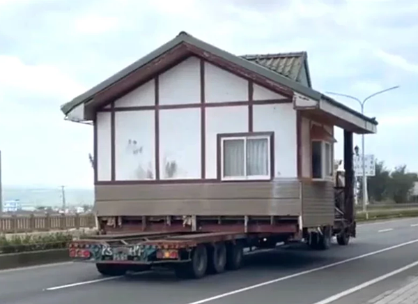 1輛載運小木屋的拖板車行駛屏東縣恆春鎮台26線恆公路上,民眾拍下影片昨天PO上網路社群,有網友戲稱是「霍爾的移動城堡」。圖/警方提供