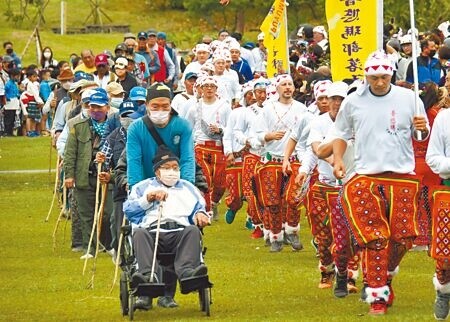 
卑南族普悠瑪部落舉行大獵祭，男性族人護衛手持棍杖的長老進入凱旋門 。（莊哲權攝）
