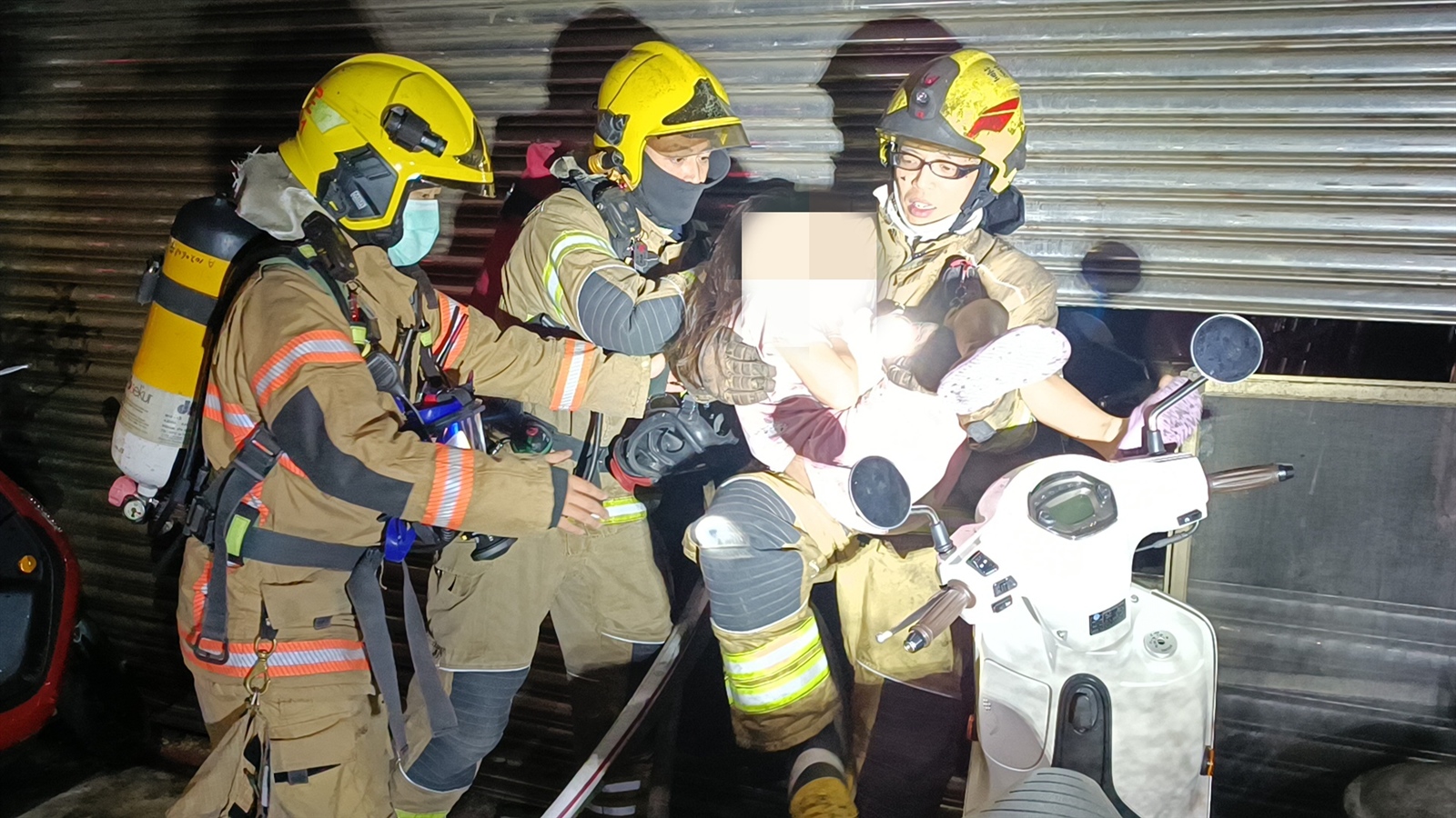 台南善化凌晨民宅濃煙， 7人急逃生幸運獲救，最小女童由消防隊員抱著救出。記者謝進盛／攝影 