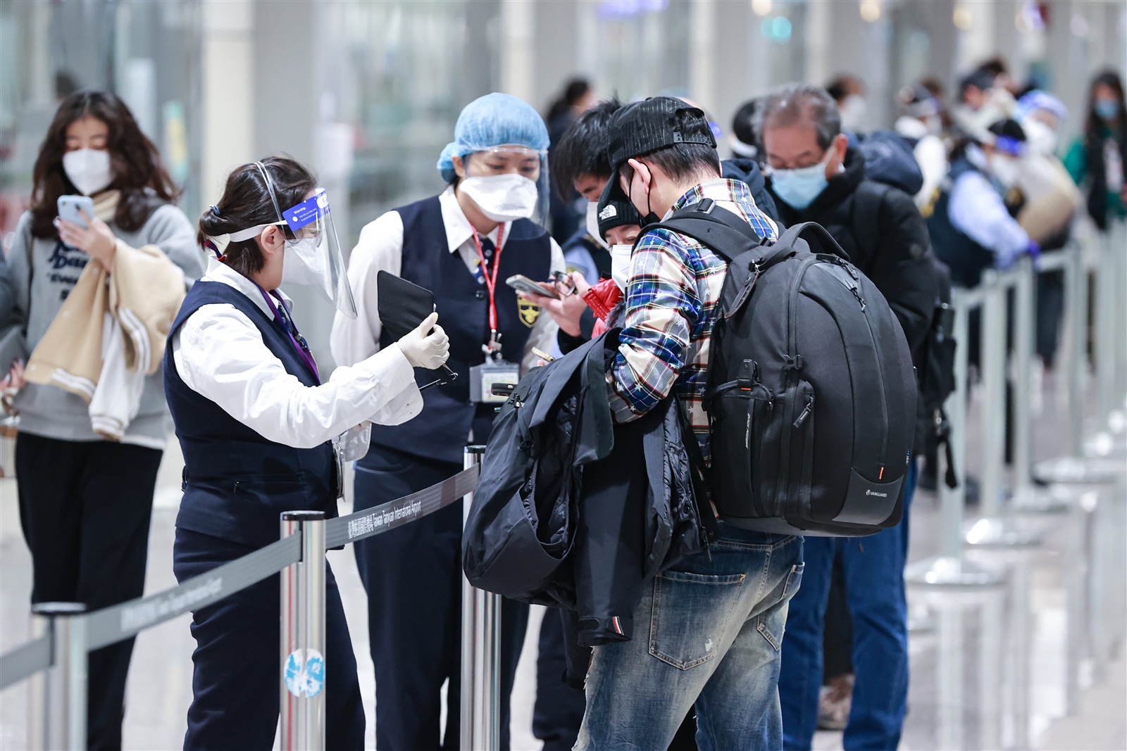 國內自元旦起針對大陸直航入境航班進行唾液PCR檢驗，圖為疾管署人員協助大陸返台旅客填寫入境檢疫健康申報。聯合報系資料照片