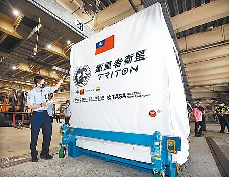 台灣首枚自製氣象衛星「獵風者」14日運抵桃園機場,準備送往法屬圭亞那發射升空,安檢人員正在檢查衛星的包裝外觀。(范揚光攝)