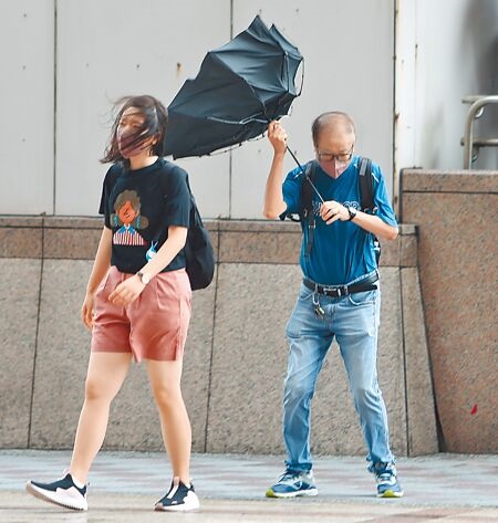 氣象局預計今下半天將解除杜蘇芮颱風警報。圖為27日大台北地區受強風襲擊，民眾外出時，雨傘被強風吹翻，行走不易。（實習攝影記者洪啟祐攝）