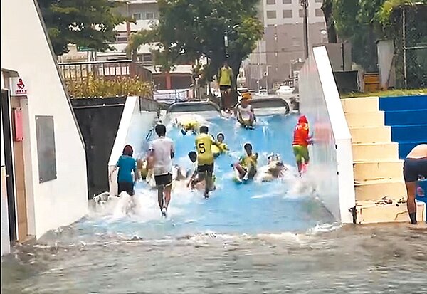 杜蘇芮颱風帶來大雨狂炸花蓮,花蓮美崙田徑場斜坡入口因大量水流形成「小型滑水道」,吸引民眾前往戲水。(翻攝畫面/羅亦晽花蓮傳真)