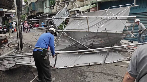 新北新莊一處工地鷹架上午受強風影響突倒塌,當場砸毀住家玻璃及屋簷,所幸未有人車受害;新北工務局、消防局、區公所及施工單位等趕緊處理後續。圖/新北工務局提供