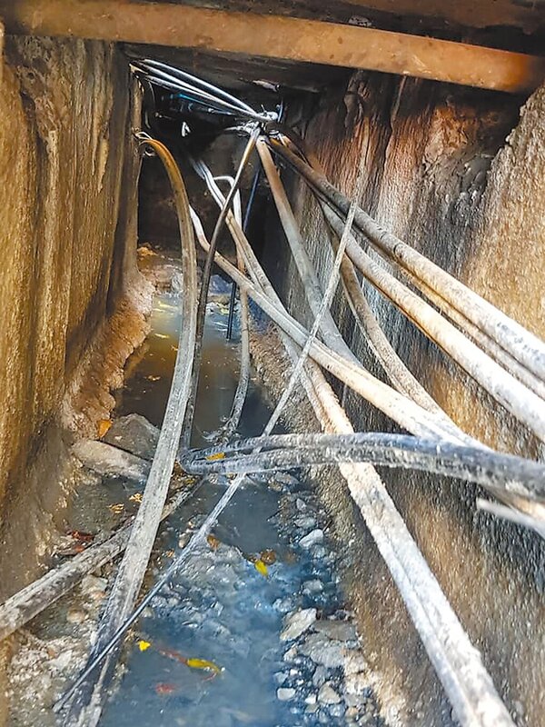 水溝內附掛纜線盤根錯節，若勾到垃圾或落葉容易導致淹水的情況。（翻攝照片／蔡依珍桃園傳真）