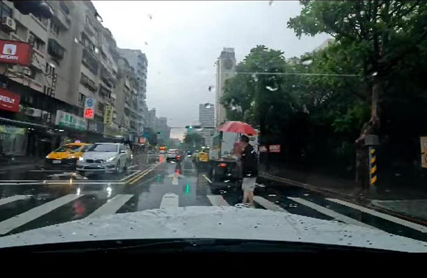 一名滿頭銀髮的阿嬤淋雨走斑馬線,藝人董至成主動攙扶過馬路,並用身體擋住來車。圖/取自「爆怨2公社」臉書社團