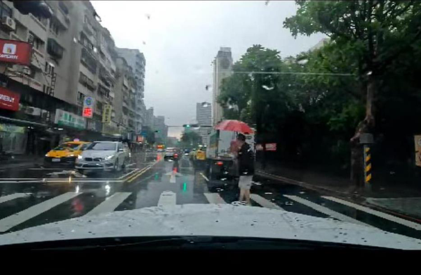 一名滿頭銀髮的阿嬤淋雨走斑馬線，藝人董至成主動攙扶過馬路，並用身體擋住來車。圖／取自「爆怨2公社」臉書社團