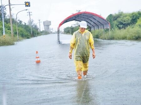 
口湖鄉子寮漁港1日滿潮位高過堤防，鄉長李龍飛腳下是漁港外的路面，淹水極為嚴重。（周麗蘭攝）
