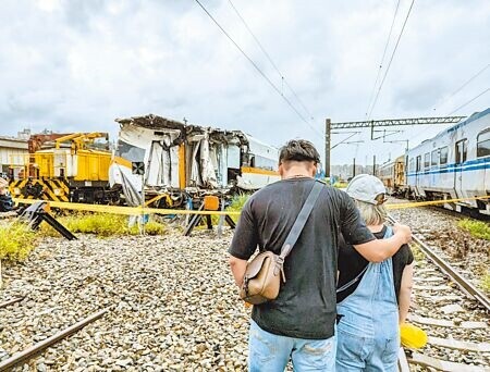 
檢警4日前往基隆七堵機務段，搜索2年前發生出軌意外的太魯閣號第1到6節車廂，倖存者陳先生（左）帶著當天沒有在車上的妻子到場關心，看著太魯閣號車廂殘骸百感交集。（張志康攝）
