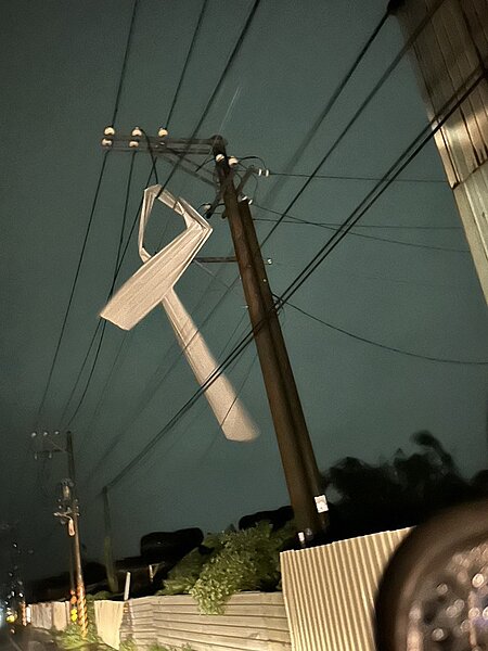 梓官區四維路一間工廠廠房屋頂的鐵皮被吹落，壓在高壓線導線上造成停電事故。圖／台電提供