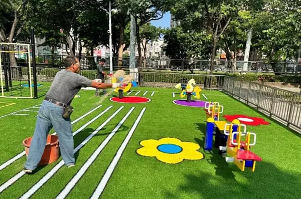 潭子運動公園新遊具鋪人工草皮,市府委託廠商鋪上專用砂,改善靜電。圖/台中市運動局提供