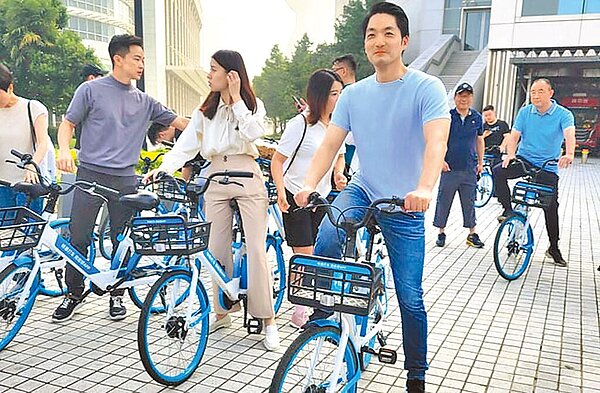 台北市長蔣萬安(前右)8月赴上海參訪,與在上海的台灣青年一同騎乘共享單車,蔣萬安盼北市可借鏡上海的無樁式共享單車,可望解決YouBike無柱可還的問題。(台北市政府提供/劉彥宜台北傳真)