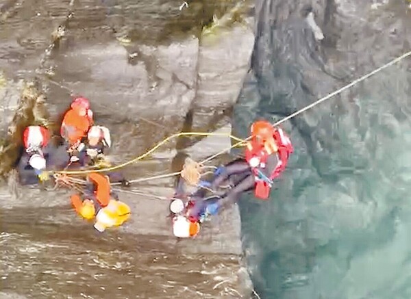 10人溯溪團挑戰屏東飛龍瀑布因大雨受困，5人平安獲救、2死3人失聯，空勤直升機21日上午成功吊掛1名受困者送醫。（屏東縣消防局提供）