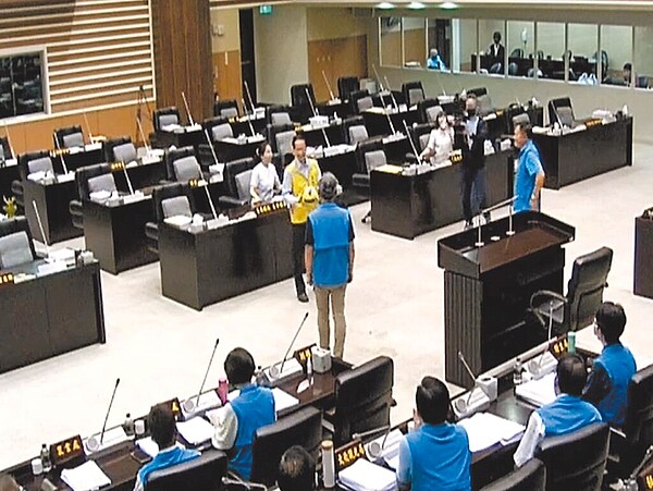 苗栗縣苑裡鎮農地重劃區部分道路破損,引起地方民怨,縣議員張顧礫(黃衣者)質疑縣府地政處、水利處互踢皮球,30日在議會質詢時,他拿出躲避球請2位處長「接球」,並要求給出答覆。(民眾提供/李京昇苗栗傳真)