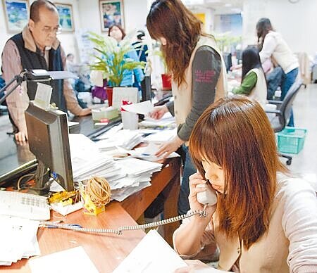 行政院拍板軍公教明年調薪4%。圖為公家機關櫃台人員忙著辦理民眾申辦文件。(本報資料照片)