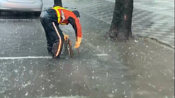 雨彈狂炸,高雄市區多處路段積水,環保局人員翻開水溝蓋,發現水溝的水都是滿的。圖/讀者提供