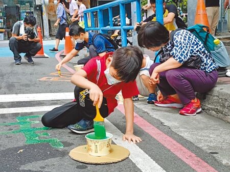 新北市政府與蘆洲國小等單位攜手共同發想的「街道設計派對：一起玩、一起走！」工作坊，小朋友在暫時增加的人行道空間上作畫。（簡立欣攝）