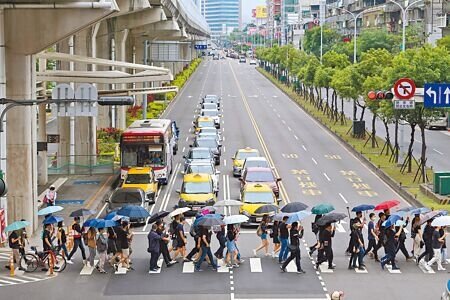 
路口停讓行人政策重回原本「人車距離3公尺」執法標準，交通部長表示，這是因為駕駛人觀念已有提升，遭網友酸爆。圖為5月行人安全大富翁活動，群眾繞行路口呼籲還路於民。（本報資料照片）
