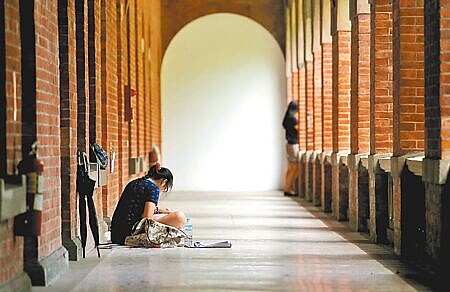 少子化猛烈衝擊,近年許多大學招不到學生面臨退場。圖為一名考生坐在走廊專心準備大考,比起以往考場的熱鬧景象,顯得冷清不少。(本報資料照片)