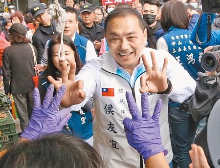 國民黨總統候選人侯友宜（中）16日到台北市南京公寓市場掃街拜票，受到攤商熱烈歡迎，他也比出三號手勢，希望大家多多支持。（趙雙傑攝）