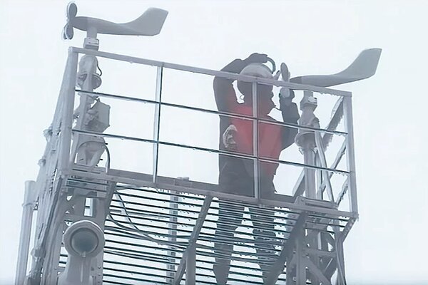 玉山氣象站昨早觀測到下雪,圖為工作人員用熱水解凍測風儀。圖/截自氣象署影片